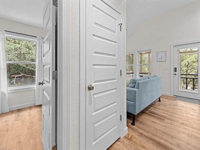 hallway with lofted ceiling and light hardwood / wood-style flooring