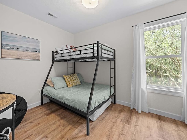 bedroom with multiple windows and light hardwood / wood-style flooring