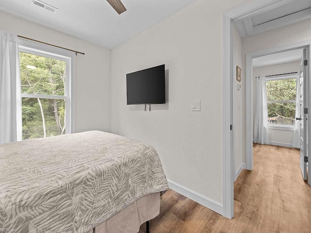 bedroom featuring ceiling fan, multiple windows, and light wood-type flooring