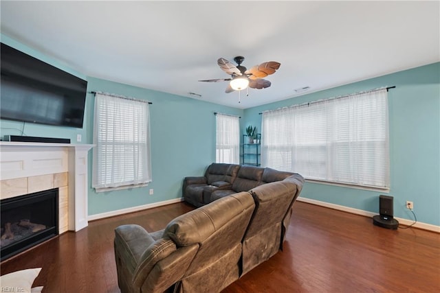 living room with a fireplace, ceiling fan, and dark wood-type flooring