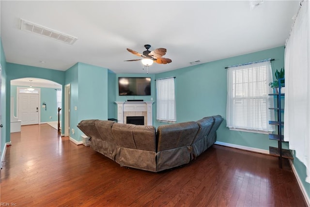 living room featuring a tile fireplace, ceiling fan, and wood-type flooring