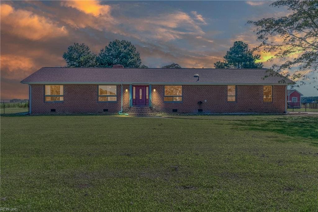 ranch-style home with crawl space, a chimney, brick siding, and a front yard