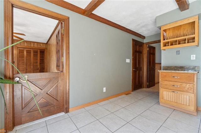 kitchen featuring ceiling fan, light tile patterned floors, wooden walls, and dark stone counters