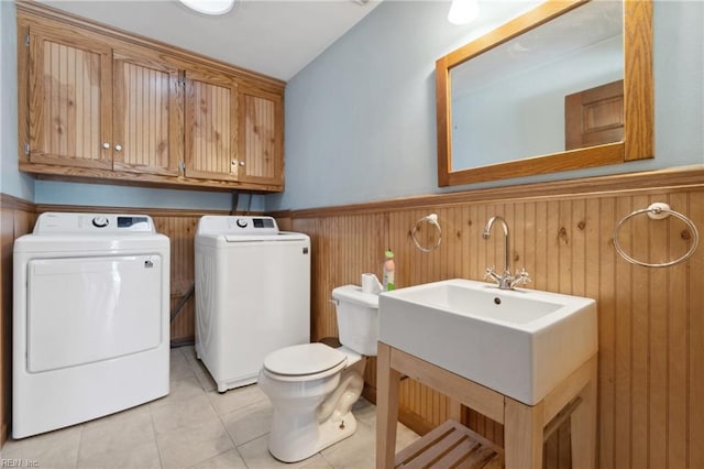 laundry area featuring washing machine and clothes dryer, wooden walls, and light tile patterned flooring