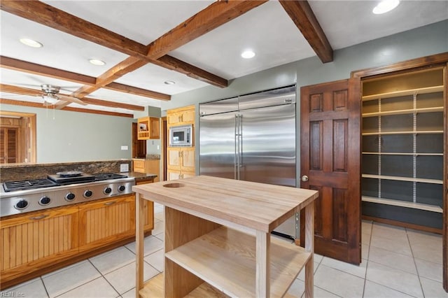 kitchen featuring built in appliances, light tile patterned floors, ceiling fan, and beamed ceiling