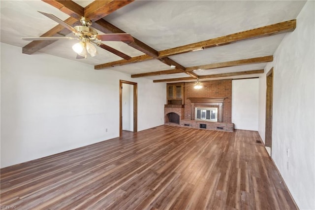 unfurnished living room with ceiling fan, beam ceiling, wood-type flooring, and a brick fireplace