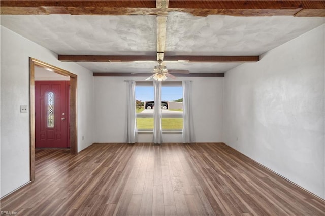 empty room featuring ceiling fan, beamed ceiling, and hardwood / wood-style flooring