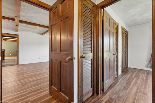 hall featuring beam ceiling and hardwood / wood-style flooring