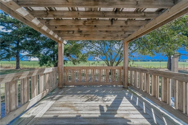 deck with a rural view and a pergola