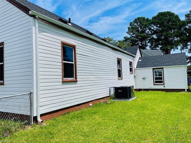 rear view of house featuring central AC unit and a yard