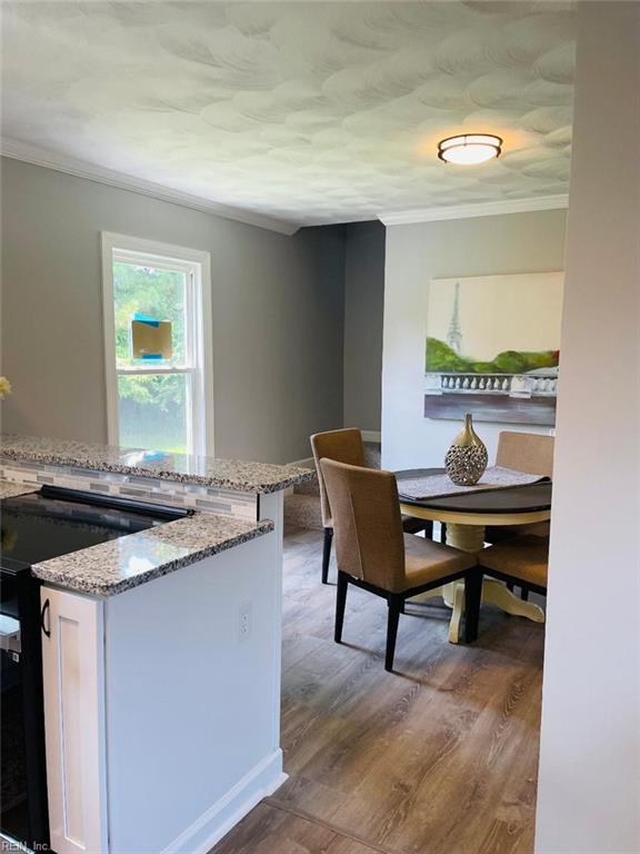 dining space with crown molding and light hardwood / wood-style floors