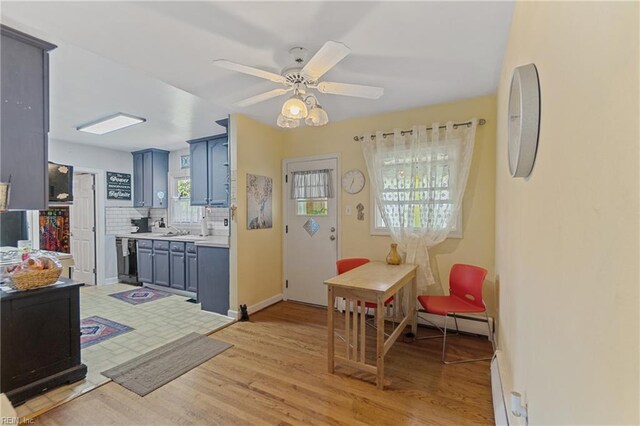 interior space with decorative backsplash, a baseboard heating unit, light wood-type flooring, and ceiling fan