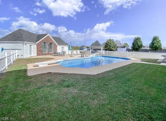 view of swimming pool featuring a patio area, a lawn, and a diving board