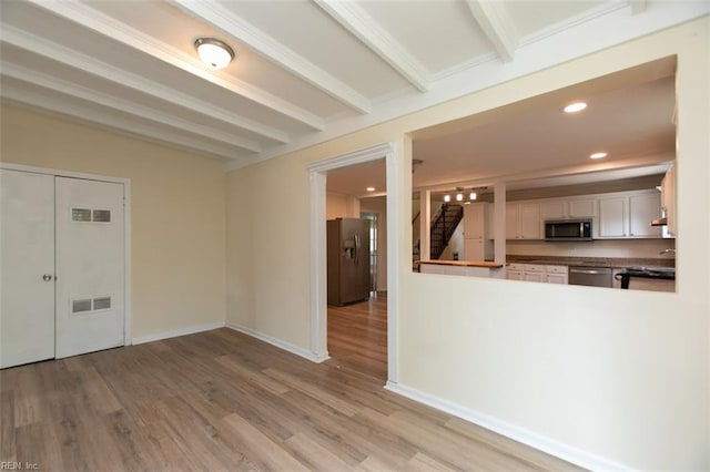 kitchen featuring beamed ceiling, light hardwood / wood-style flooring, stainless steel appliances, and white cabinetry