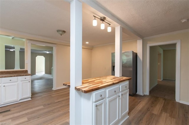 kitchen with white cabinetry, light wood-type flooring, wood counters, and a textured ceiling