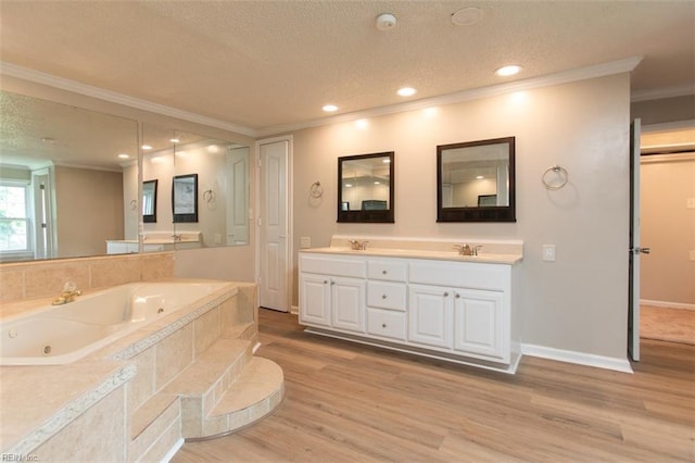 bathroom featuring tiled bath, a textured ceiling, hardwood / wood-style floors, and double vanity