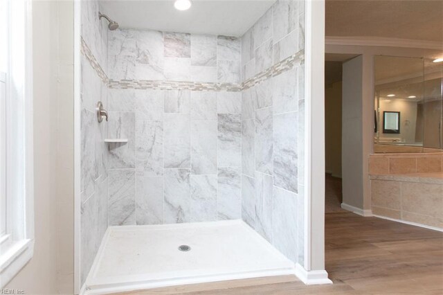 bathroom with crown molding, hardwood / wood-style floors, and a tile shower