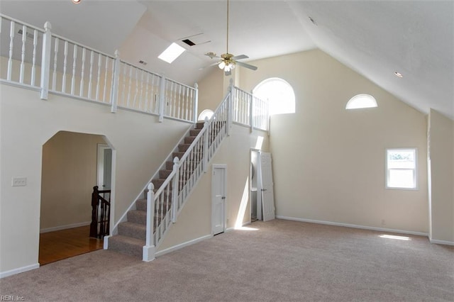 unfurnished living room with high vaulted ceiling, carpet, and ceiling fan