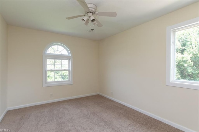 unfurnished room featuring a healthy amount of sunlight, light colored carpet, and ceiling fan