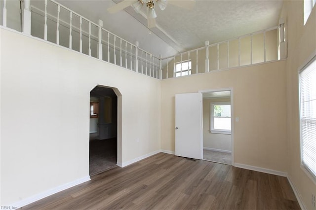 spare room featuring ceiling fan, hardwood / wood-style flooring, and a towering ceiling