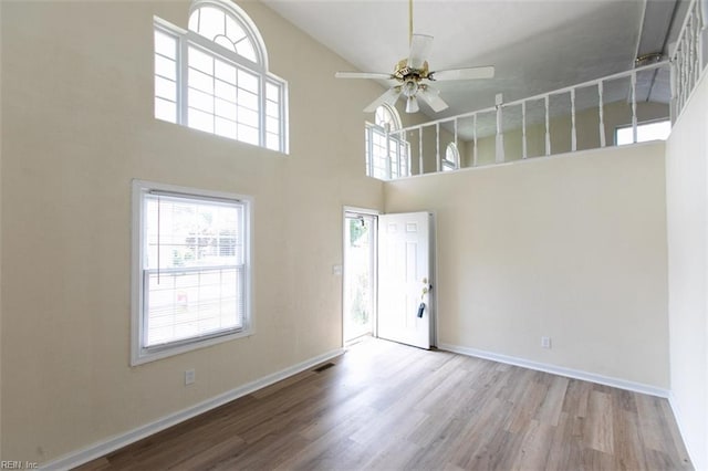 unfurnished room featuring hardwood / wood-style flooring, a high ceiling, and ceiling fan