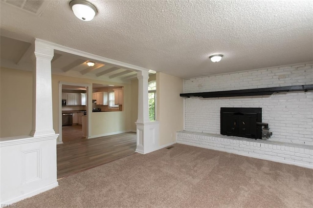 unfurnished living room featuring a fireplace, carpet, ornate columns, and a textured ceiling