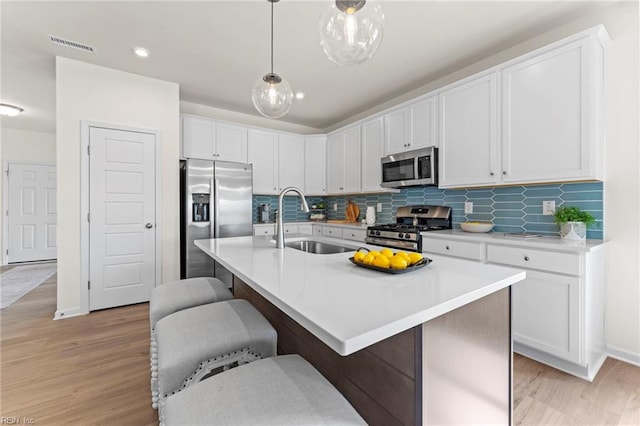 kitchen featuring stainless steel appliances, an island with sink, sink, and a breakfast bar