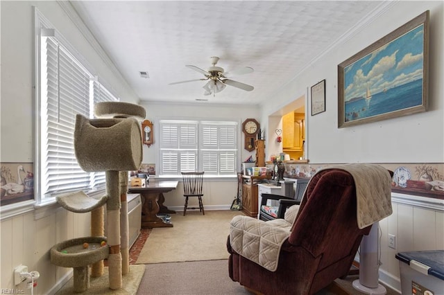 carpeted home office featuring a ceiling fan, a wainscoted wall, and ornamental molding