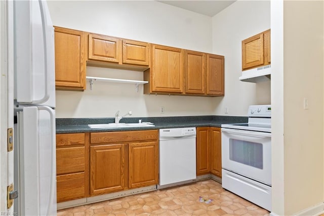kitchen featuring white appliances, under cabinet range hood, a sink, and dark countertops