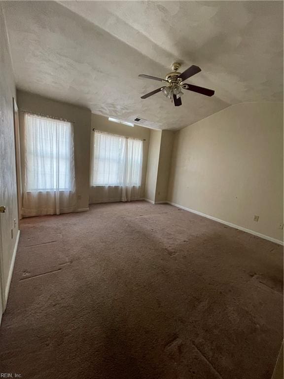 carpeted empty room with baseboards, a textured ceiling, lofted ceiling, and ceiling fan