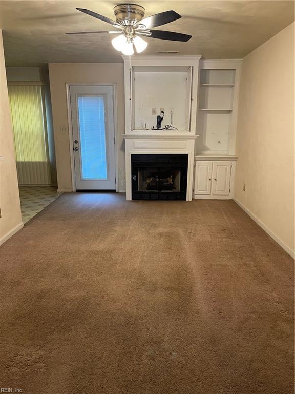 unfurnished living room with baseboards, carpet floors, ceiling fan, and a fireplace