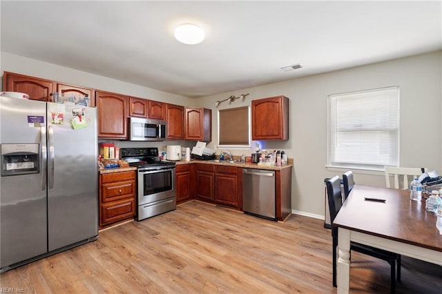 kitchen with light wood-type flooring, stainless steel appliances, and sink