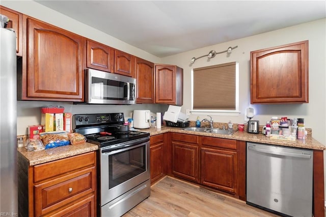 kitchen with light hardwood / wood-style flooring, sink, stainless steel appliances, and light stone countertops