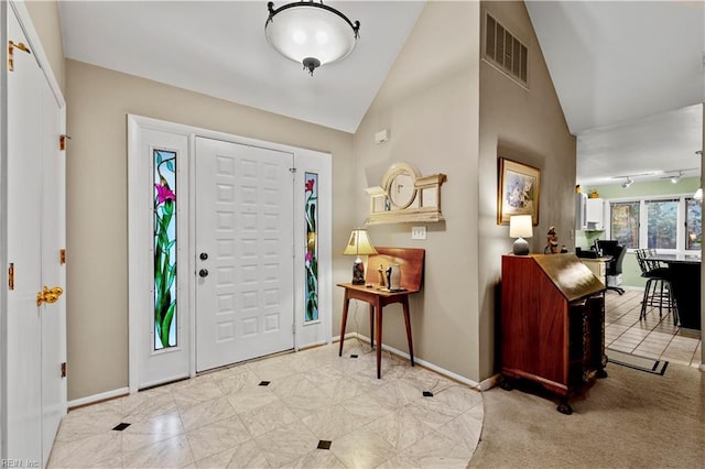 entryway with lofted ceiling, track lighting, and light tile patterned floors