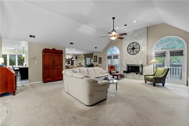 living room with light colored carpet, a wealth of natural light, a fireplace, and ceiling fan