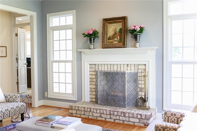 living area featuring hardwood / wood-style flooring and a brick fireplace