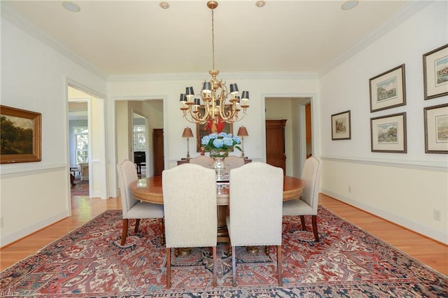 dining room featuring hardwood / wood-style flooring, ornamental molding, and a chandelier