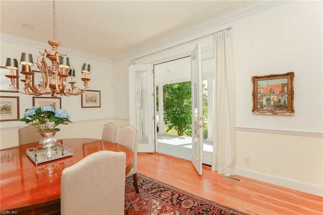 dining room featuring crown molding, hardwood / wood-style floors, and a notable chandelier