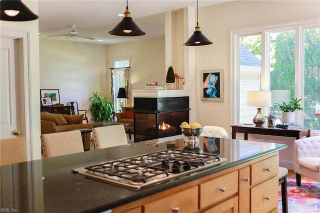 kitchen featuring ceiling fan, light brown cabinetry, stainless steel gas cooktop, and hanging light fixtures