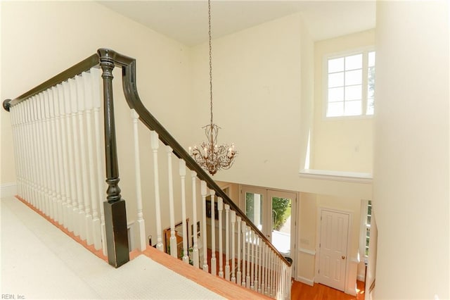 staircase featuring wood-type flooring, plenty of natural light, and a notable chandelier