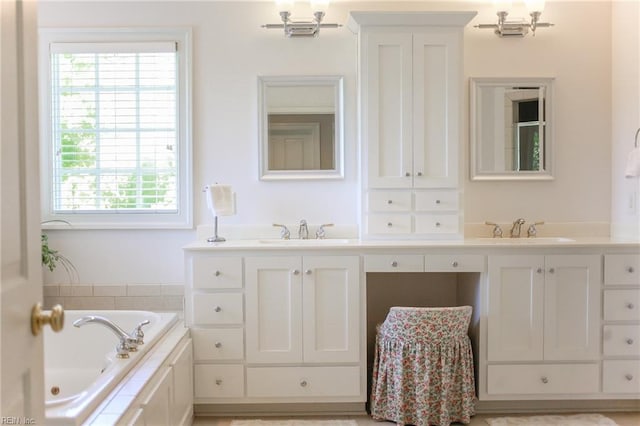 bathroom featuring a relaxing tiled tub and vanity