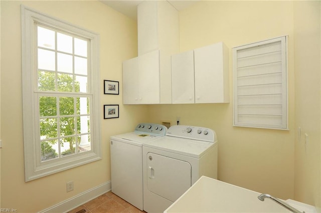 laundry area featuring cabinets, plenty of natural light, light tile patterned floors, and washer and clothes dryer