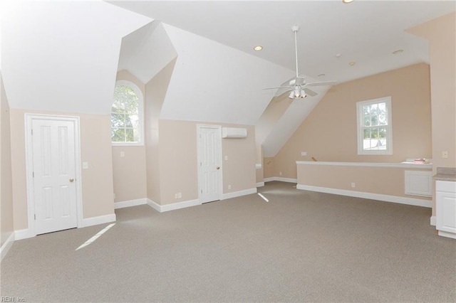 additional living space featuring plenty of natural light, light colored carpet, a wall mounted AC, and lofted ceiling