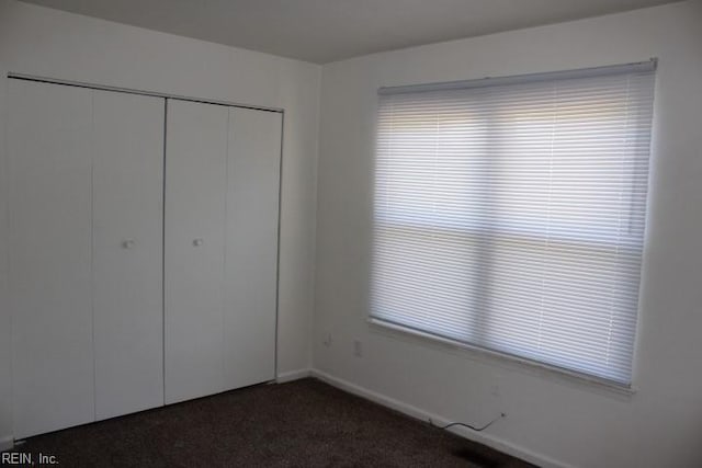 unfurnished bedroom featuring dark carpet and a closet