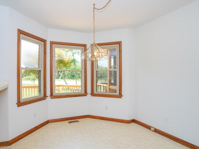 carpeted spare room with an inviting chandelier