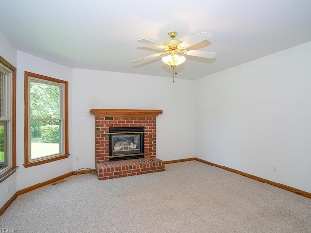 unfurnished living room featuring a brick fireplace, ceiling fan, and carpet