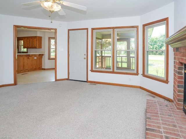 unfurnished living room featuring ceiling fan, light carpet, and a brick fireplace