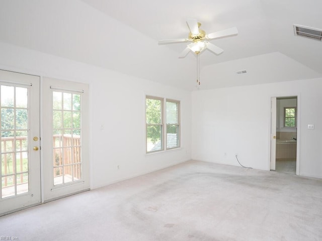 empty room featuring lofted ceiling, light colored carpet, french doors, and ceiling fan