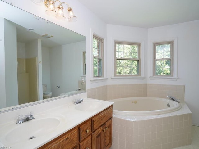 bathroom with vanity, a relaxing tiled tub, and toilet