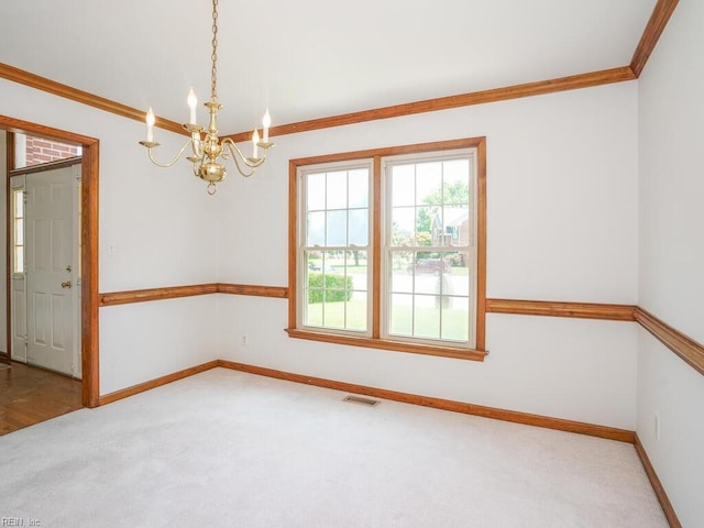 carpeted empty room with ornamental molding and a chandelier